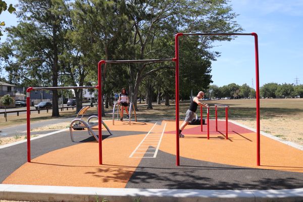 People using various outdoor exercise equipment. 